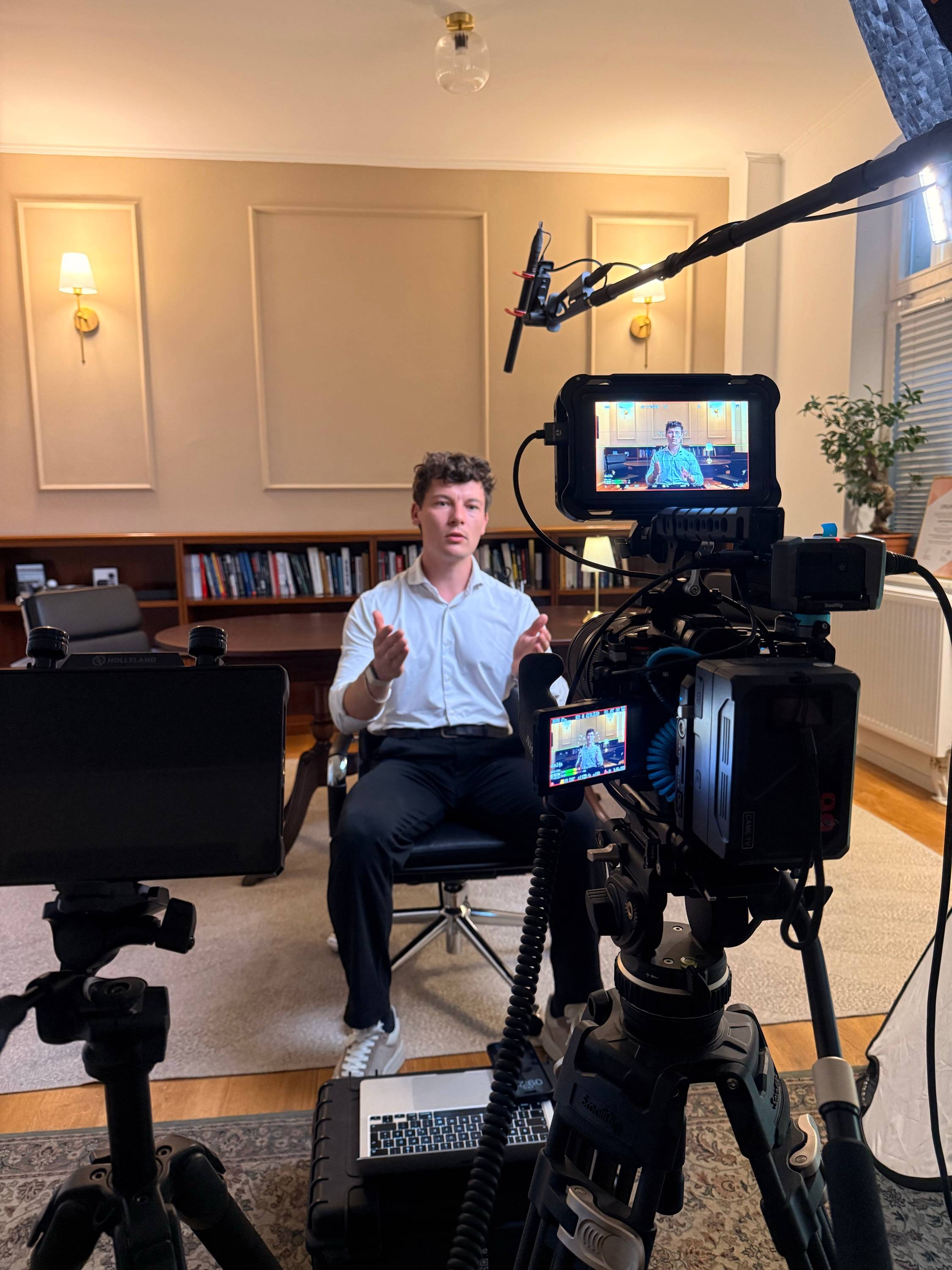 Cedric spricht vor der Kamera eine Videobotschaft ein, im Vordergrund Kamera und Monitor
