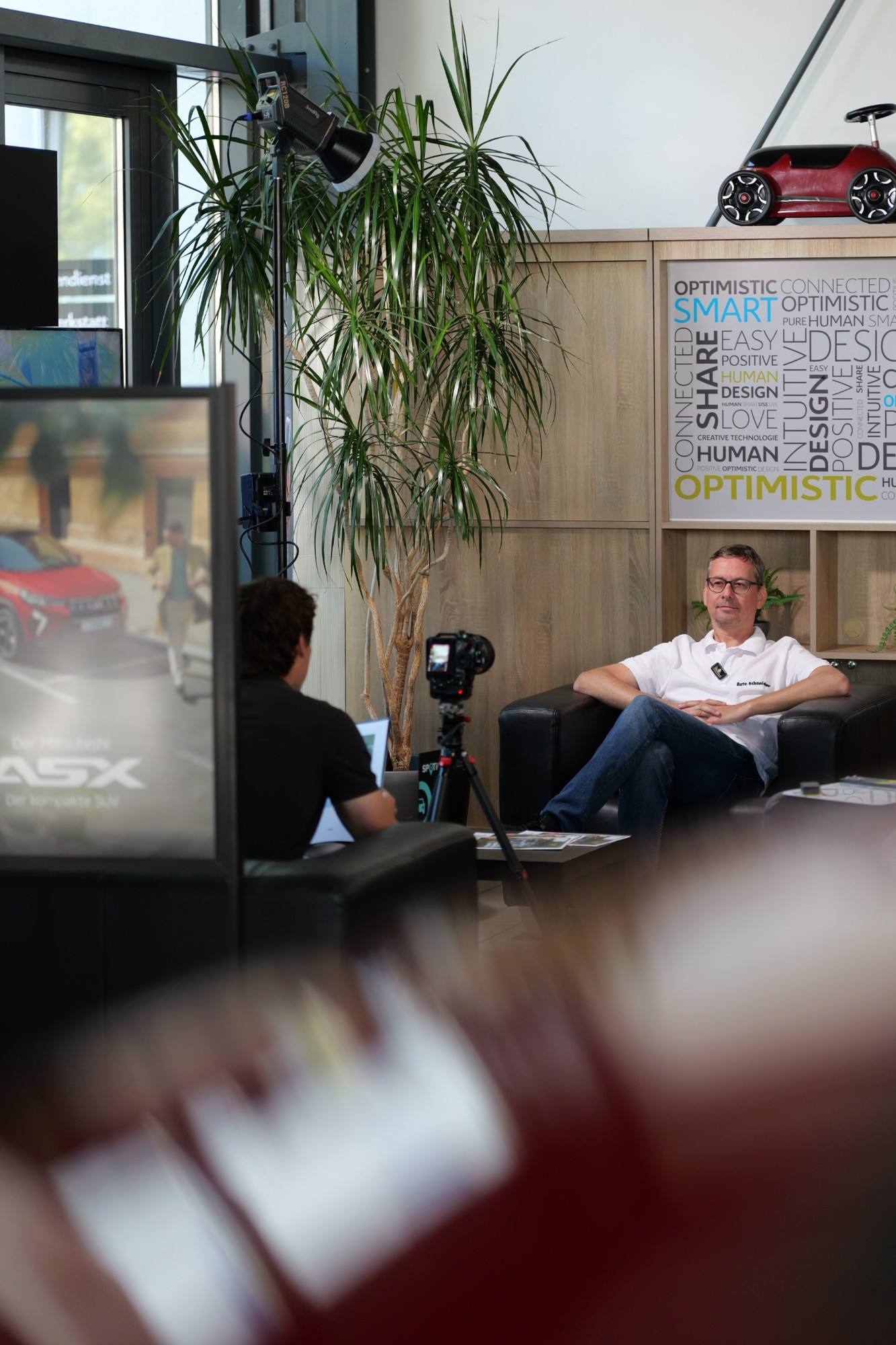 Benjamin Schneider im Interview beim Dreh in seinem Autohaus, im Vordergrund Kamera und Licht